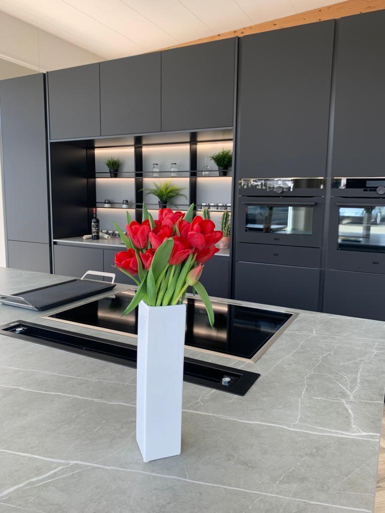 Anthrazitfarbene Küche mit roten Tulpen auf der Kochinsel
